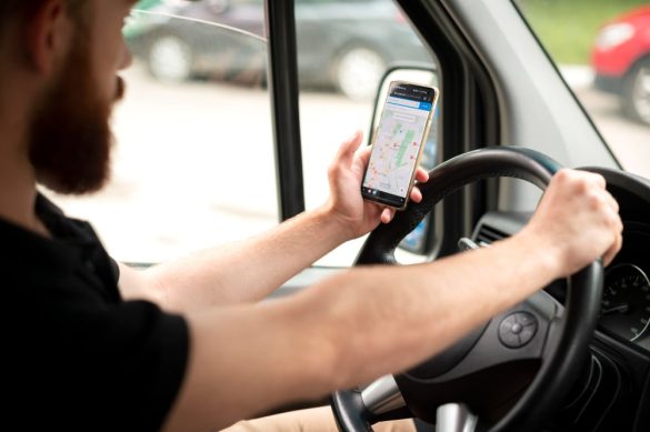 Un localisateur GPS compact noir posé sur une carte routière, avec des éléments numériques en arrière-plan, suggérant le suivi de véhicule
