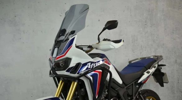 Moto Honda Africa Twin blanche avec un pare-brise fumé.