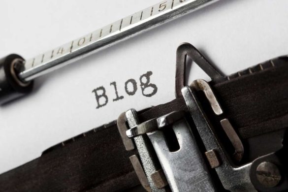 Gros plan sur une machine à écrire vintage en cours de frappe, le mot 'Blog' est lisible sur la feuille de papier blanche.